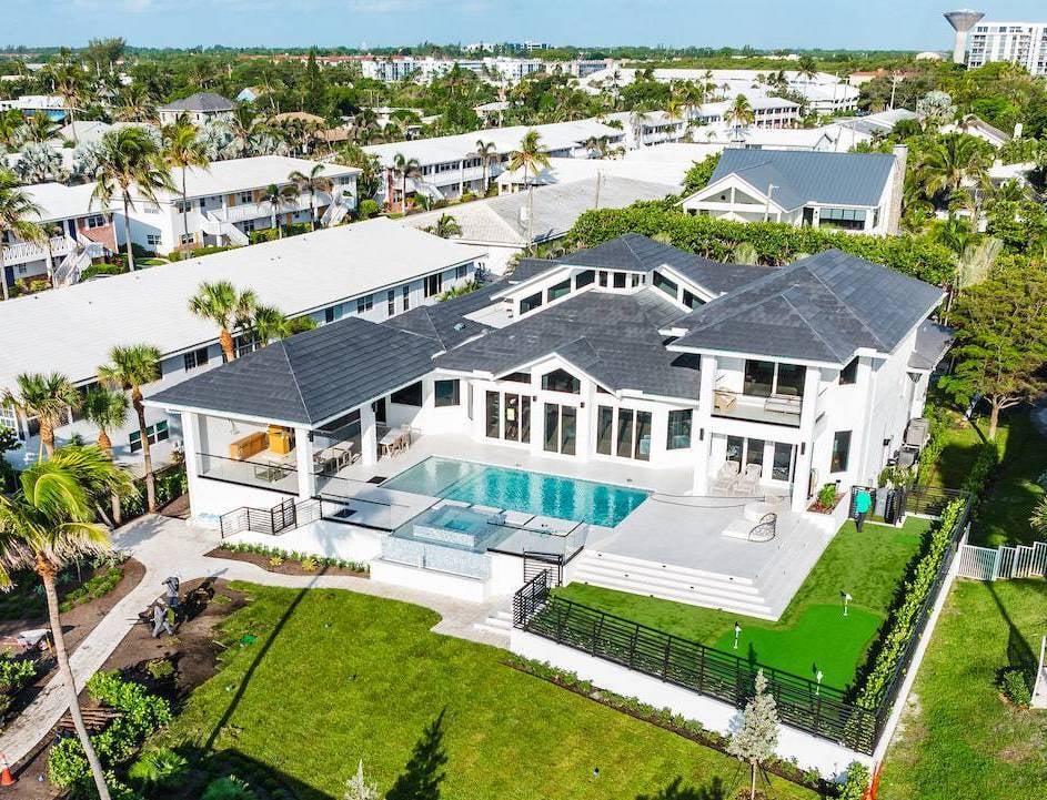 Aerial view of luxury estate home with pool, patio, and professional landscape installation in Palm Beach County