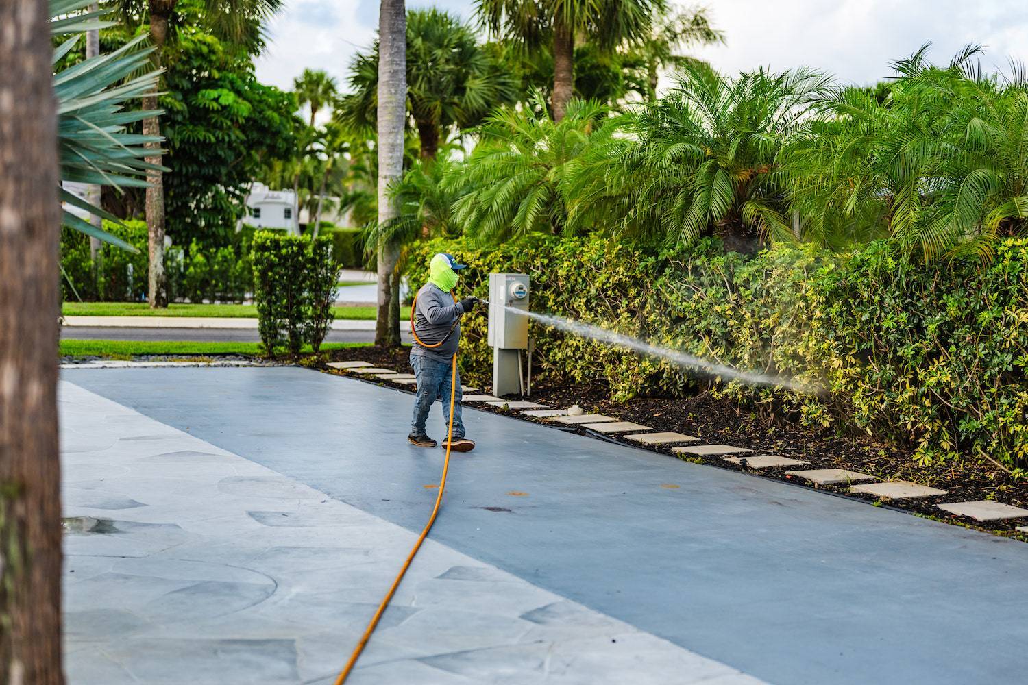 Commercial landscape services applying pest control along driveway in Palm Beach, FL