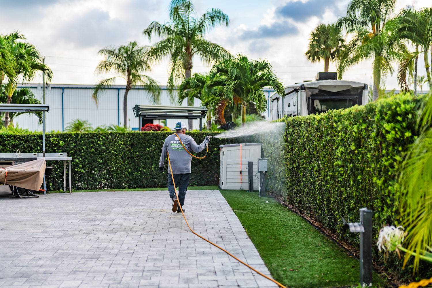 Landscape maintenance crew spraying hedges at luxury mobile home community in West Palm Beach, FL