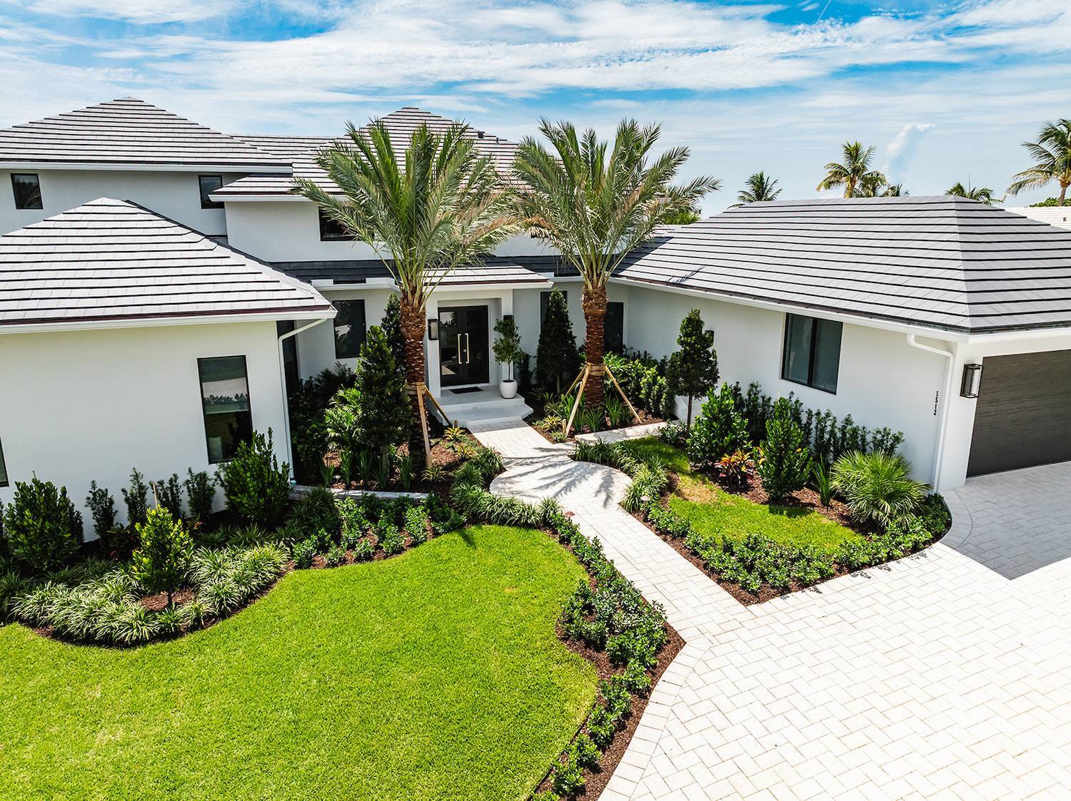 Luxury modern estate home with manicured landscape design and palm trees in Palm Beach County