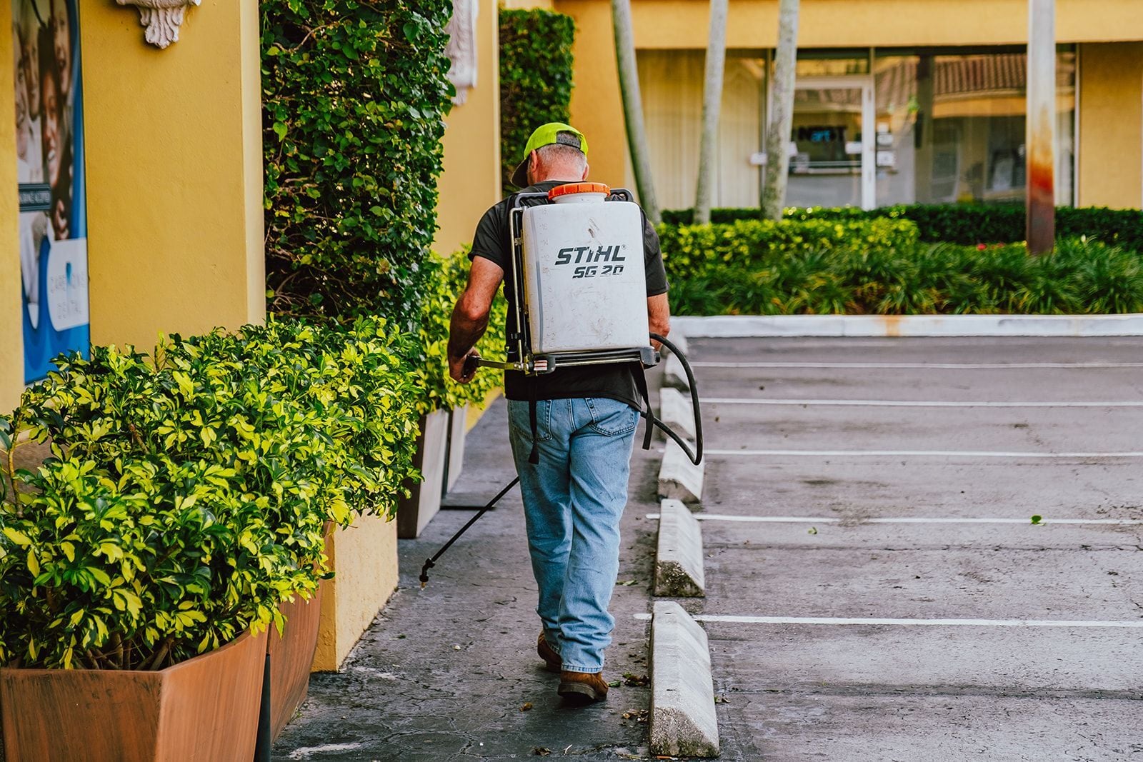 Commercial landscaping technician performing fertilization and pest control services for commercial property landscape maintenance in West Palm Beach, FL