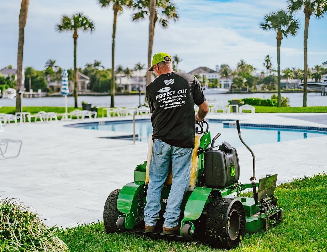Commercial lawn maintenance mowing turf around waterfront HOA pool area in West Palm Beach, FL